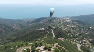 Paraşüt ya da yamaç paraşütü sporu deneyimi. Adrenalin açık hava sporu. Malibu 'nun yukarısındaki doğada sakin ve güzel bir zaman. İki paraşütçü dağın tepesinde destansı yaz günışığında uçuyor.