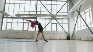 Pembe saçlı, güzel ve sağlıklı bir kızın büyüleyici esnemesi. 30 'lu yaşlarındaki aktif ve güçlü bir kadın parlak bir spor salonunda amuda kalkıyor. Yüksek kalite 4k görüntü