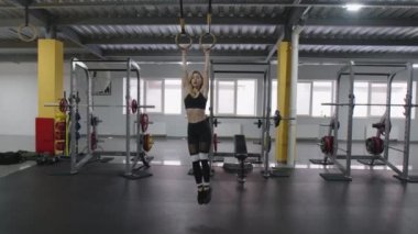 Parlak bir spor salonunda karın kaslarını çalıştıran bir bayan sporcu. 30 'lu yaşlarda genç, sarışın bir kadın mekik çekerken barda takılıyor. Yüksek kalite 4k görüntü