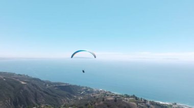 Malibu dağlarında Los Angeles 'ın üzerinde uçan olağanüstü bir paraglider. Özgürlük kavramı. Güneşli bir günde dağların üzerinden uçan maceracı spor videoları. Amerika 'da popüler yamaç paraşütü bölgesi