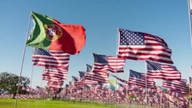 Kırmızı kamera, Portekiz 'in altın günbatımı arka planında rüzgarda dalgalanan yüksek kaliteli bayraklar, arkasında Amerika Birleşik Devletleri bayrakları. Uluslararası turizm ve seyahat ekonomisi kavramı
