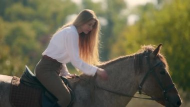 Güzel kız sırtüstü otururken at besliyor. Kırsalda güneşli ve güzel bir günün tadını çıkaran bir atlı kadının yakın çekimi. Yüksek kalite 4k görüntü