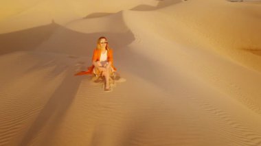 Doğada meditasyon yapan ve hayatı düşünen, parlak geleceği hayal eden bir kadın. İlham, özgürlük, sağlıklı yaşam tarzı, meditasyon konsepti. Kum tepelerinde gezgin altın gün batımına bakıyor