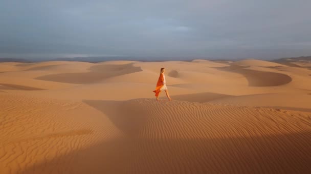 １０００年的少妇 穿着橙色的绒衣 光着脚 在金色的夕阳下 在沙丘上飞舞 把胳膊举到空中 醉生梦死 青春幸福4K — 图库视频影像