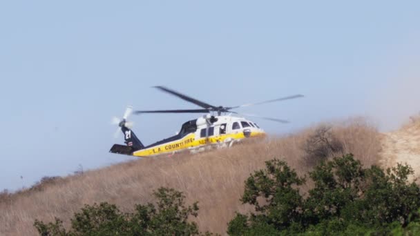 山火事の上を飛ぶ消防ヘリコプターの4K壮大なショット ロサンゼルス郊外地域の山の上のブッシュ火災の上に上昇する熱波 カリフォルニア州の暑い夏の気候変動により 自然は燃えています — ストック動画