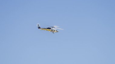 Hollywood tepelerinde Los Angeles banliyölerinde yangın helikopteri görülmüş. Los Angeles İtfaiye Departmanı helikopteri açık mavi gökyüzünde uçuyor. Yangın helikopteri yangını söndürüyor