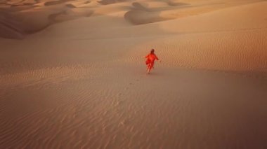 Özgür kız çölde çıplak ayakla koşar. Altın sarısı günbatımında kum tepecikleriyle ya da gün doğumunda. Sandy Dune Parkı 'nda koşan gezgin kız. Mutlu özgür kız doğada eğleniyor. Rüya kavramı