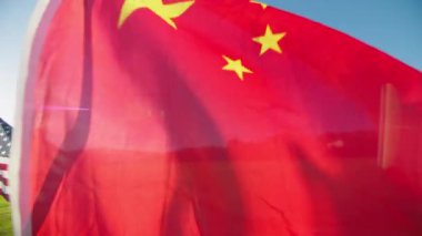 Yakından çekilen görüntülerde Çin 'in altın günbatımı arka planında rüzgarda dalgalanan kırmızı bayrağı, arkasında Amerika Birleşik Devletleri' nin birçok bayrağı var. Uluslararası turizm kavramı, seyahat iş ekonomisi