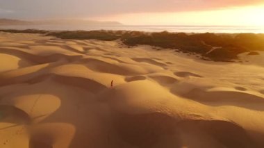 Sinema robotu, altın turuncu gün batımında kum tepeleri çölünde yürüyen bir kızın etrafında uçuyor. Sandy Dune Parkı 'nda koşan gezgin kız. Mutlu özgür kız doğada eğleniyor. Rüya konsepti hava