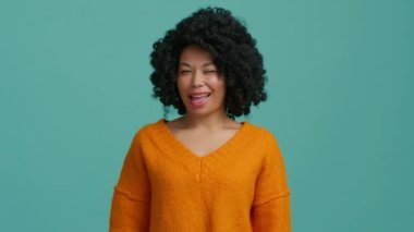Afrika kökenli Amerikalı kadın, siyah tenli güzel bir kadın kameraya bakıp göz kırpıyor. Sağlıklı beyaz dişli kız gülümsüyor. Afro-Amerikan kadın portresi 4K