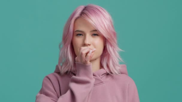 スローモーションスタジオは カメラにまっすぐに見えるピンクのパーカーで20代のピンクの髪の若い女性を撮影し ジッパーを示し 沈黙を可視化口ジェスチャーを閉じ スローモーションで話をしたくない停止 — ストック動画