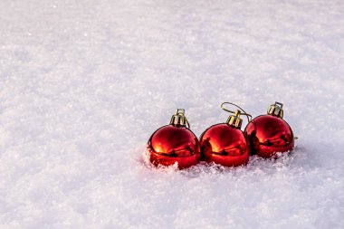 Beyaz kar üzerinde üç kırmızı noel ağacı topu