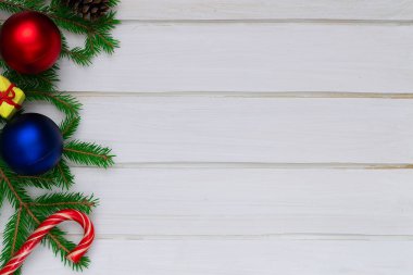 Noel zamanı, toprak, yeşil köknar dalları, kırmızı ve mavi top, şekerler, hediye kutusu, beyaz tahtalar.