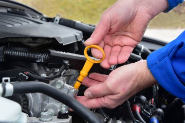 Seviye kontrol çubuğuyla araba motorundaki yağ miktarını kontrol ediyorum.