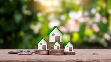 Bozuk paralar ve bulanık yeşil arka planda sahte bir ev modeli. Gayrimenkul Yatırım Fikirleri İpotek ve konut kredisi faiz oranları