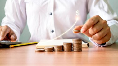 İş adamı bir yığın madeni para tutuyor. Ticari yatırımlardan elde edilen karı en üst düzeye çıkarma kavramı..