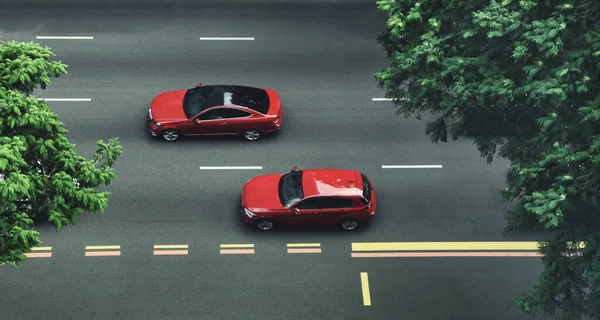 İki kırmızı araba gölgeli, ağaçlarla kaplı şehir caddesinde geziniyor..