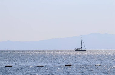 Mavi deniz dalgaları güneşte parlıyor ve bir yat.