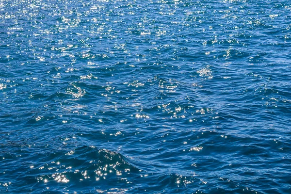 Μπλε κύματα στη λιακάδα λάμπουν ως φόντο επιφάνεια. Καλοκαιρινές διακοπές — Φωτογραφία Αρχείου
