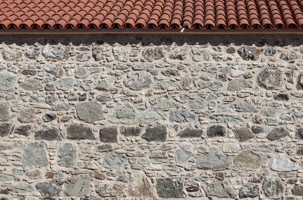 Partie d'un vieux mur de pierre et toit. Fond naturel ou texture Photo De Stock