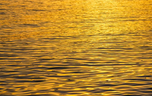 Gouden zee golven in zonsondergang gloeien als oppervlakte achtergrond. Begrip zomervakantie — Stockfoto