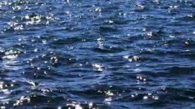 Güneş ışığındaki mavi deniz dalgaları yüzey arkaplanı gibi parlıyor. Yaz tatili kavramı