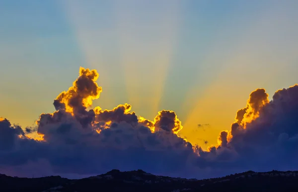 Background from a beautiful sunset with clouds and sunlights over mountanous coast — Stock Photo, Image