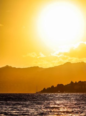 Ege Denizi kıyısında dağlar ve teknelerle güzel bir gün batımı. Yaz tatili ve doğa konsepti