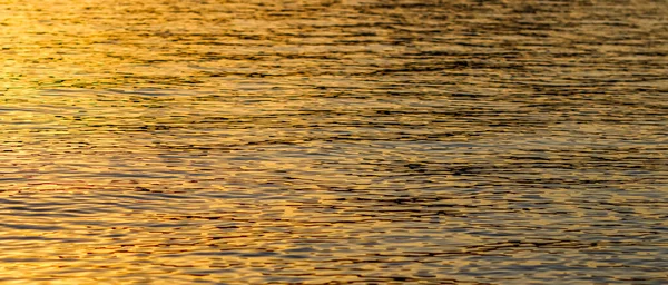 Gouden zee golven in zonsondergang gloeien als oppervlakte achtergrond. Begrip zomervakantie — Stockfoto