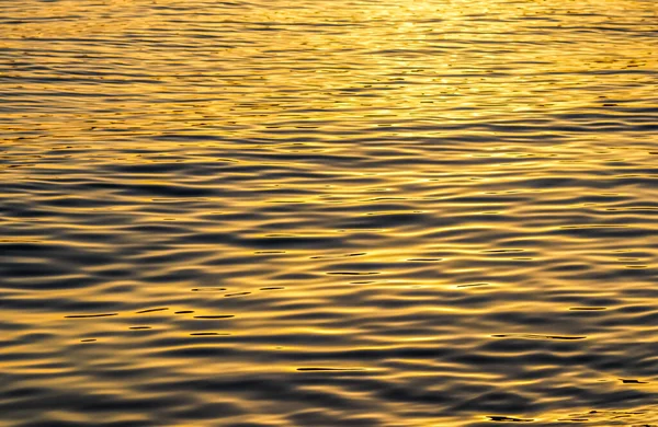 Gouden zee golven in zonsondergang gloeien als oppervlakte achtergrond. Begrip zomervakantie — Stockfoto