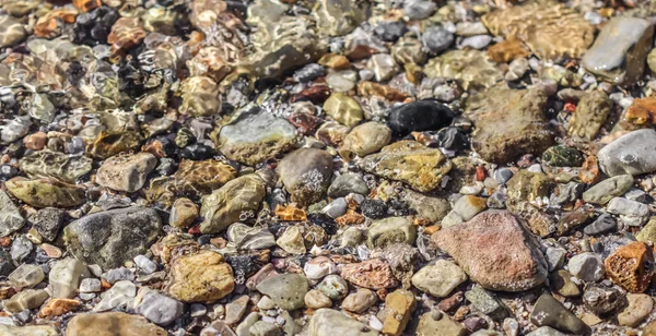 Hintergrund sind Steine und fließende Wellen am Meeresstrand. Sommerferienkonzept — Stockfoto