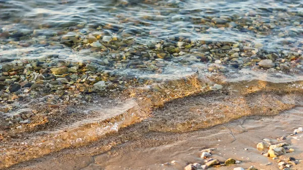 Hintergrund von Sand, Steinen und fließenden Wellen am Meeresstrand. Sommerferienkonzept — Stockfoto
