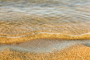 Gün batımında kumlu sahilde dalgalanan dalgalar. Yaz tatili geçmişi