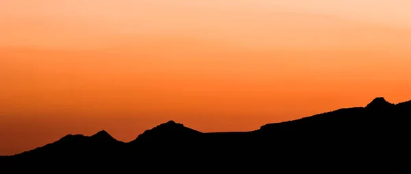 Háttér egy gyönyörű színes naplemente a sziluett a hegyek — Stock Fotó