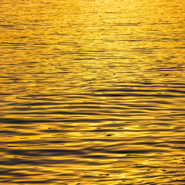 Gouden zee golven in zonsondergang gloeien als oppervlakte achtergrond. Begrip zomervakantie — Stockfoto