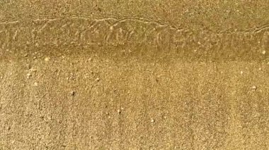 Denizin altın kumlu sahilinde dalgalanan dalgaların arka planı. Yaz tatili ve doğa konsepti