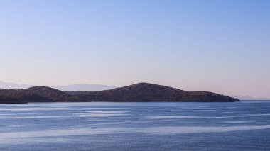 Sabahları deniz, dağlar ve ufukta mavi gökyüzü. Sakin deniz manzarası ve kıyı doğası kavramı.
