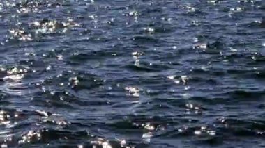 Güneş ışığındaki mavi deniz dalgaları yüzey arkaplanı gibi parlıyor. Yaz tatili kavramı