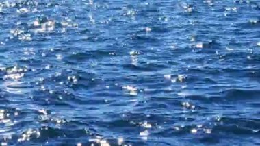 Güneş ışığındaki mavi deniz dalgaları yüzey arkaplanı gibi parlıyor. Yaz tatili kavramı