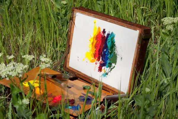 Målarens fallet på gräs med palett, konstnärligt verktyg och abstrakt målning — Stockfoto