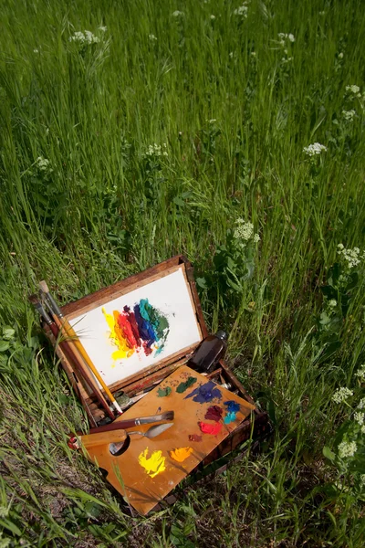 Målarens fallet på gräs med palett, konstnärligt verktyg och abstrakt målning — Stockfoto