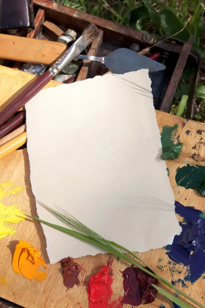 Papier texturé sur palette avec instruments de peintre sur l'herbe — Photo