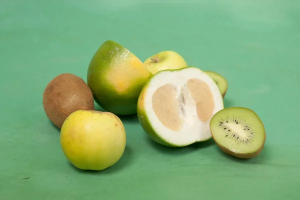 Oroblanco und andere grüne Früchte auf grünem Hintergrund — Stockfoto