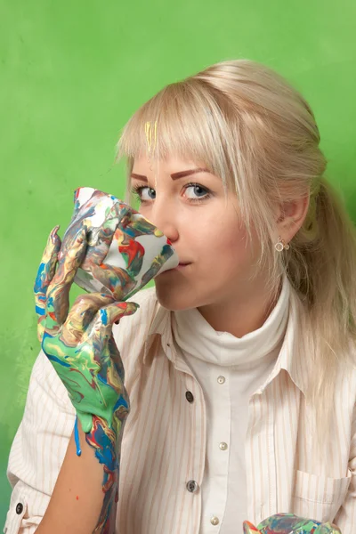 Young attractive girl with a colored hands drinking from a smudged cup — Stock Photo, Image