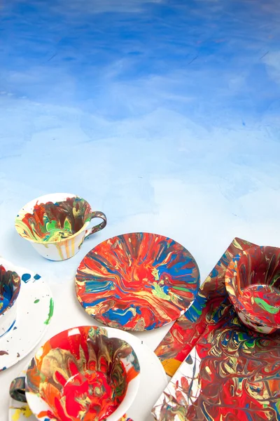 Scheda con tazze e piattini tutti macchiati di vernice su sfondo bianco e blu — Foto Stock