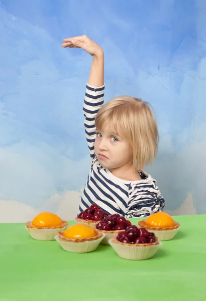 Menina com cara engraçada dançando atrás de tortas de cereja e geléia de pêssego — Fotografia de Stock