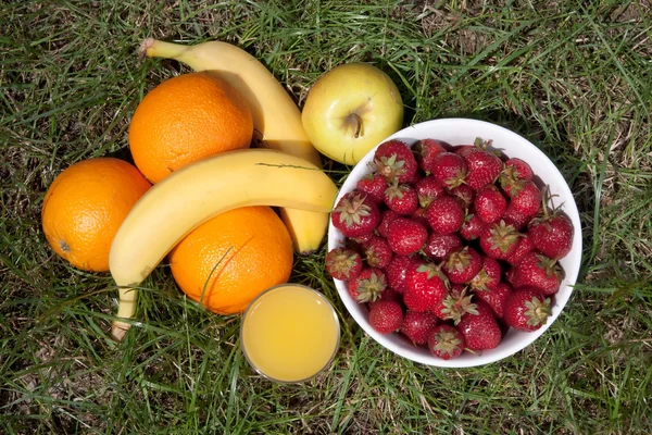 Strawberries, oranges, bananas, apple and a glass of orange juice — Stock Photo, Image