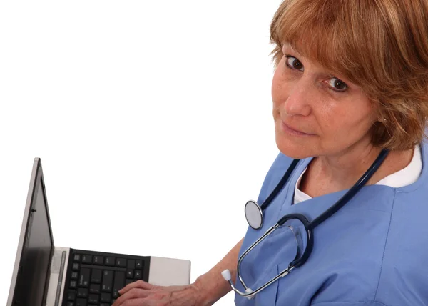 Krankenschwester schaut auf Laptop auf — Stockfoto