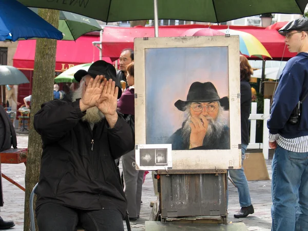Public painter on Montmartre screening his face and instead showing self-portrait — Stock Photo, Image