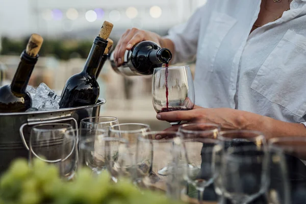 POURING RED WINE AT SOCIAL EVENT LIFE WEDDING PARTY OR OTHER LUXURY EVENT.